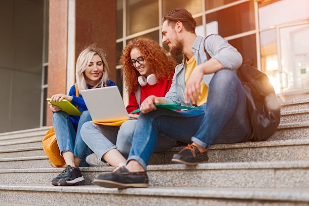 Group of happy university students sitting on stairs