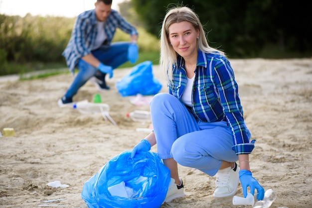 Group of happy volunteers with garbage bags cleaning area in park