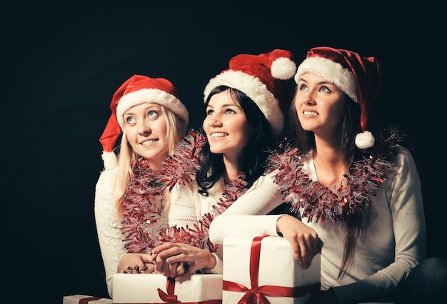 Group of happy women in costumes of santa claus and christmas shopping