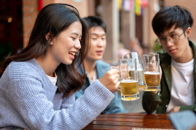 幸せな若いアジア人友達のグループがバーでビールを飲み話し合っている