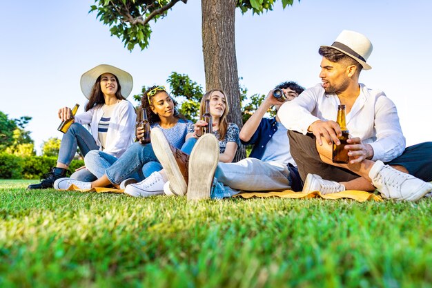 Gruppo di giovani felici e diversificati multirazziali gen z persone in una festa all'aperto che bevono birra dalla bottiglia