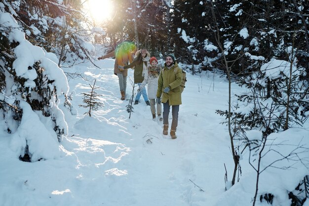 Foto gruppo di giovani amici felici che si divertono nella foresta invernale