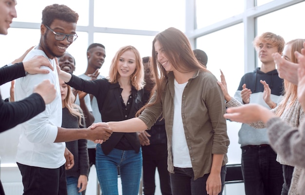 group of happy young people congratulating their colleague