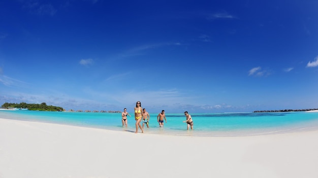 Группа счастливых молодых людей веселится на пляже с белым песком в прекрасный летний день.