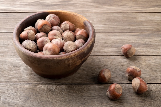 A group of hazelnuts in a bowl over wooden table.