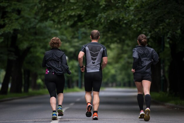 都市公園でジョギングする健全な人々のグループ、朝のトレーニングでランナーチーム