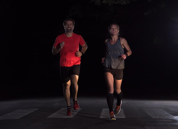 group of healthy people jogging in city park, runners team at night training