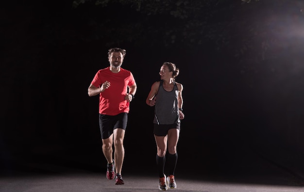 group of healthy people jogging in city park, runners team at night training