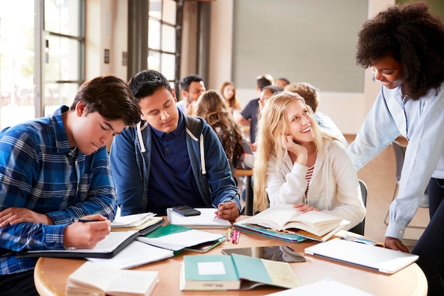 Gruppo di studenti delle scuole superiori con insegnante femminile che lavora alla scrivania