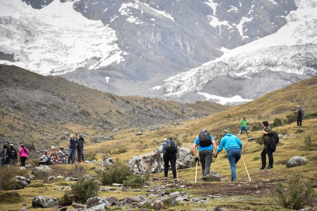 A group of hikers are hiking in a valley with mountains in the background.