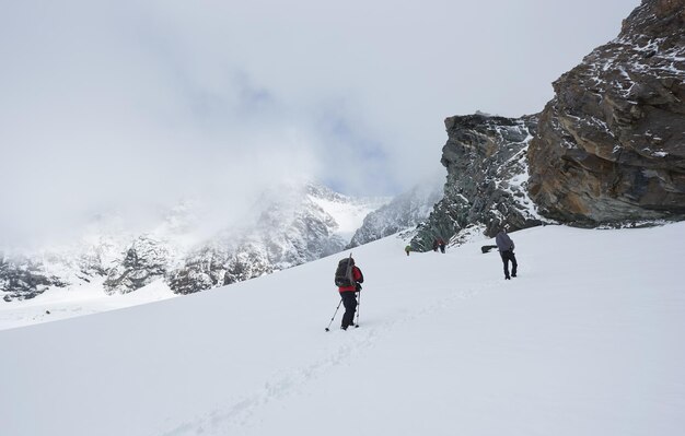 Group of hikers climbing the hill covered with snow