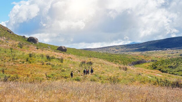 Photo group of hikers going through sun lit valley during descent from pic boby in andringitra national park. view from behind, no persons recoginizable