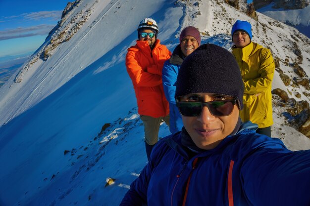 Photo group of hikers, tourists or friends stands on top of the mountain taking a photo