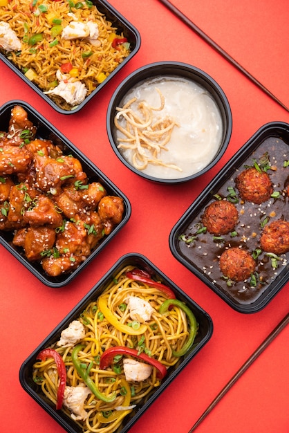 Group of home delivered indo chinese food in plastic packages,
containers&or boxes containing&schezwan noodles, fried
rice, chilli chicken, manchurian and soup.