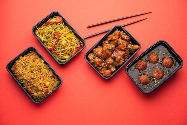 Group of home delivered indo chinese food in plastic packages,\
containers&or boxes containing&schezwan noodles, fried\
rice, chilli chicken, manchurian and soup.