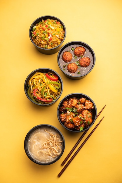 Photo group of home delivered indo chinese food in plastic packages, containers or boxes containing schezwan noodles, fried rice, chilli chicken, manchurian and soup.