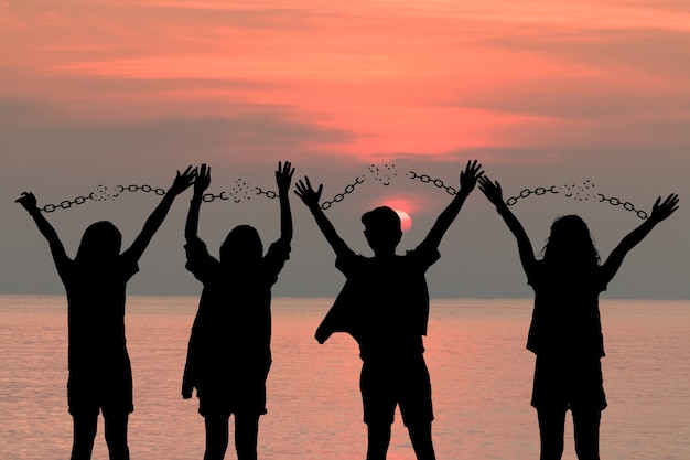 Foto l'immagine dell'ombra umana del gruppo della catena delle mani umane è assente, ottieni la libertà, nel cielo al tramonto