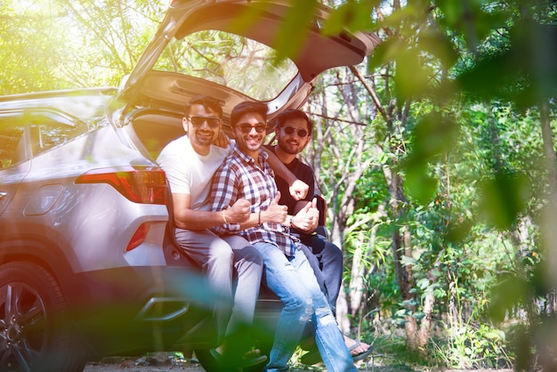 여름 도로 여행 자동차의 열린 트렁크에 앉아 인도 아시아 젊고 매력적인 친구의 그룹
