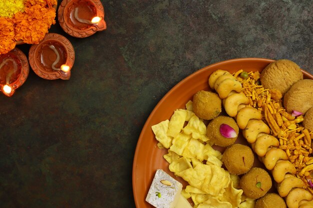 Group of Indian assorted sweets or mithai with diya, diwali snacks or diwali food or diwali sweets