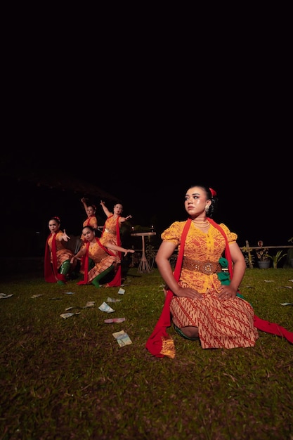 A Group of Indonesian dancers performing on the stage with a red scarf and traditional orange dress inside the festival