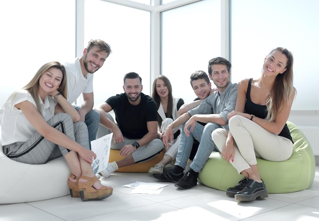 Группа инициативных молодых людей, сидящих в новом офисе, концепция стартапа