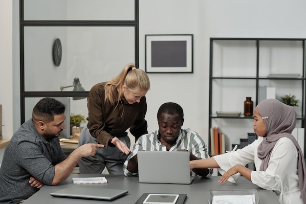 Group of intercultural displeased employees bullying african american man