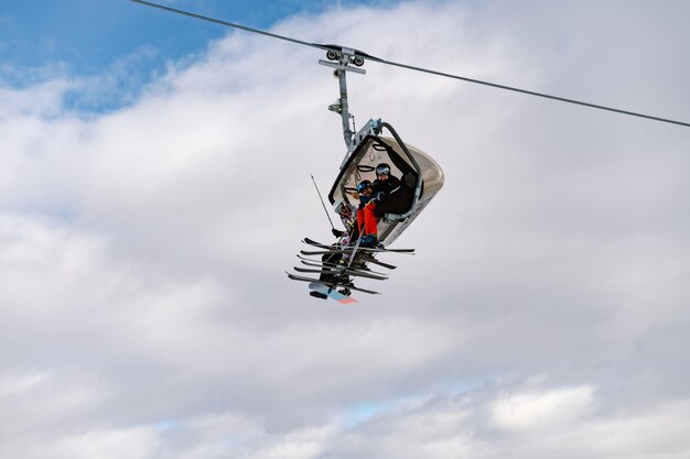 a group of international friends takes a ski lift to the top of a snowy mountainSkiers on the ski