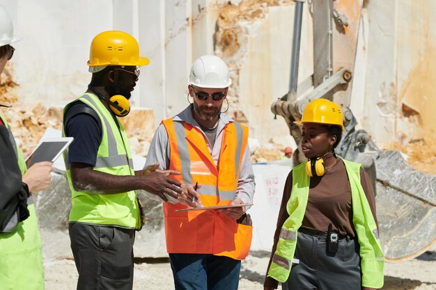 Group of interracial workers of quarry discussing working plan at meeting