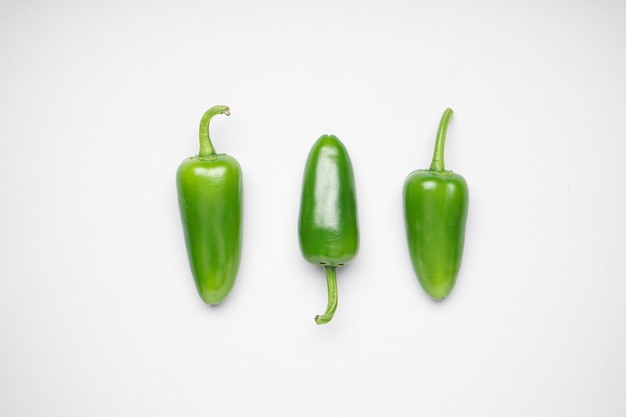 Group of jalapeno peppers on a white background, flat lay. Green chili pepper.