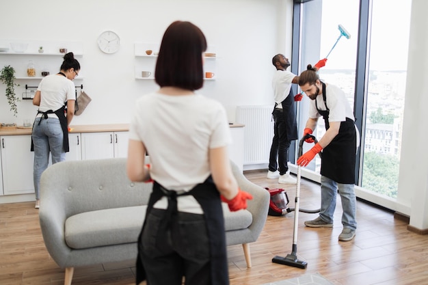 Photo group of janitors in uniform cleaning office with cleaning equipment