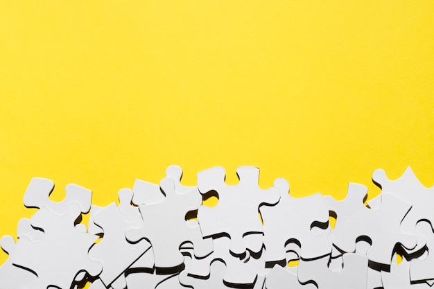 Photo group of jigsaw puzzle pieces at the bottom of yellow backdrop