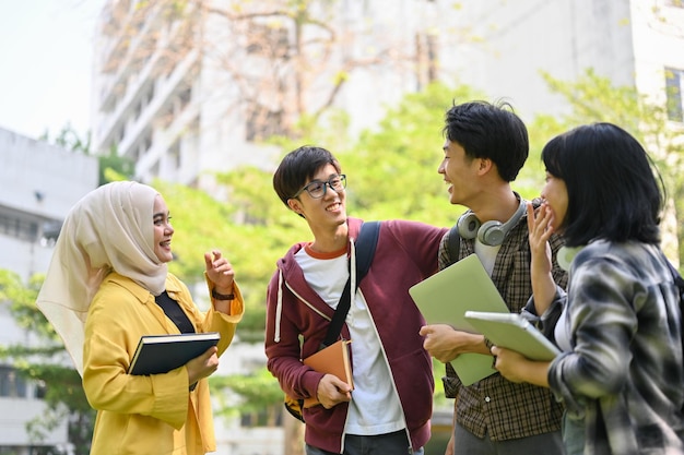 喜びに満ちたアジアの多様な大学生のグループが、キャンパスの公園で会話を楽しんでいます