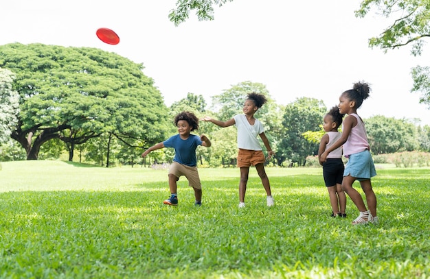 Photo group kids african american little girl and boy have fun playing and throwing flying disc in park