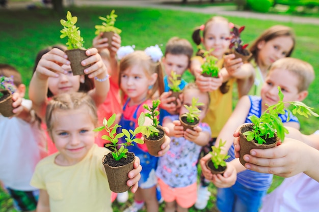 group of kids holding plants in flowerpots