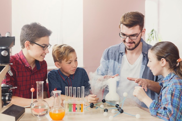 Photo group of kids with teacher doing chemical experiment with liquid nitrogen in laboratory, copy space. early development, education, diy, innovation concept. stem education.