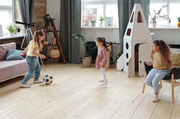 Gruppo di bambine che giocano a calcio insieme nella stanza di casa