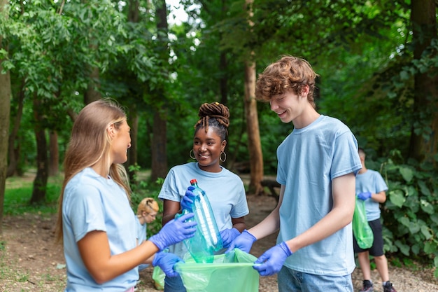 A group of local people gather to clean up their local park Mixed age groups collect garbage They squat in nature and collect garbage