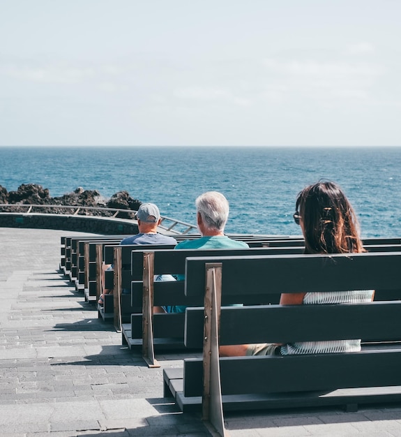 Group of Lonely Old People Sitting Alone on Benches by the Sea Looking at horizon over Ocean water