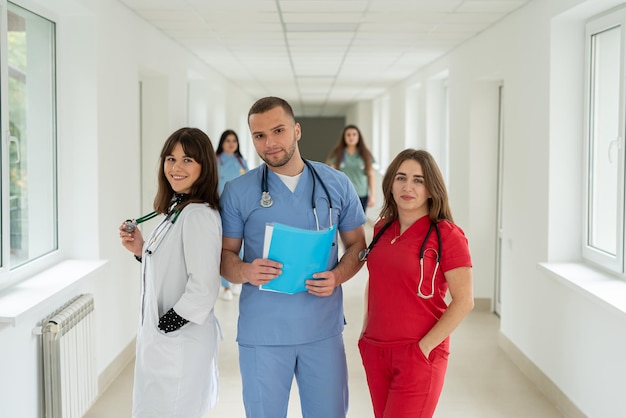 Group of man and two woman nurse stand at hospital corridor