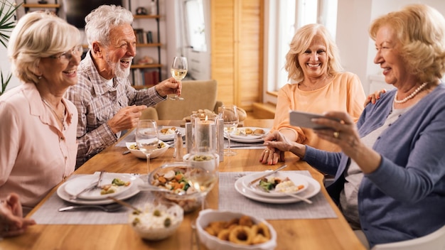 Group of mature friends laughing while talking at dining table at home