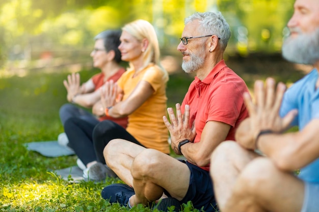 Foto gruppo di persone mature che meditano insieme nella posizione del loto all'aperto