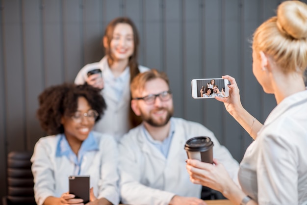 Gruppo di studenti di medicina che si divertono a fotografare con i telefoni durante la pausa caffè in classe