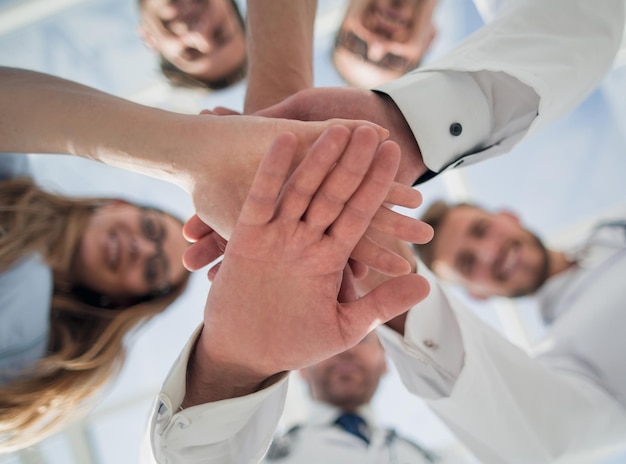 Foto gruppo di stagisti medici in camice da laboratorio con stetoscopi in piedi in cerchio tenendosi per mano