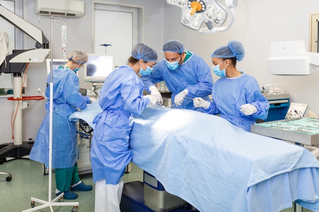 Группа медицинской бригады срочно делает хирургическую операцию и помогает пациенту в операционной в больнице Медицинская бригада проводит хирургическую операцию в яркой современной операционной