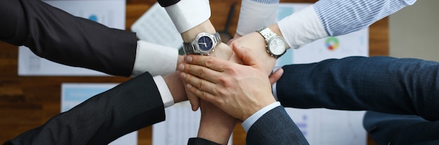 Group men in suits hold out their hands in unity