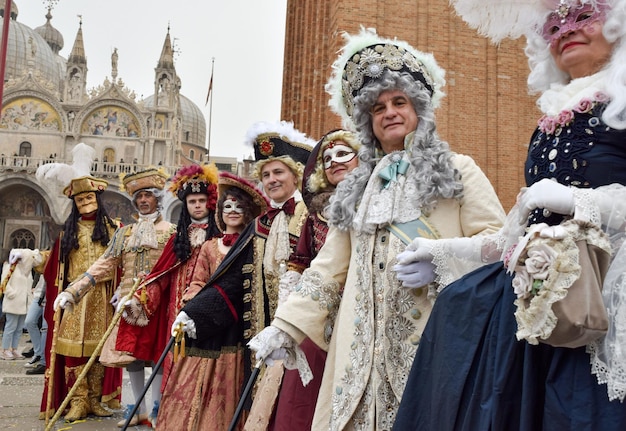 正真正銘の現代的な衣装でベネチアのカーニバルのためにドレスアップした男性と女性のグループ