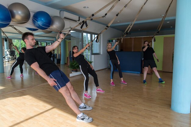 Group of Men and Women Exercising With Suspension Training Trx