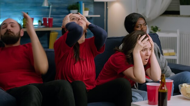 Group of mixed race sport fans watching football match on television