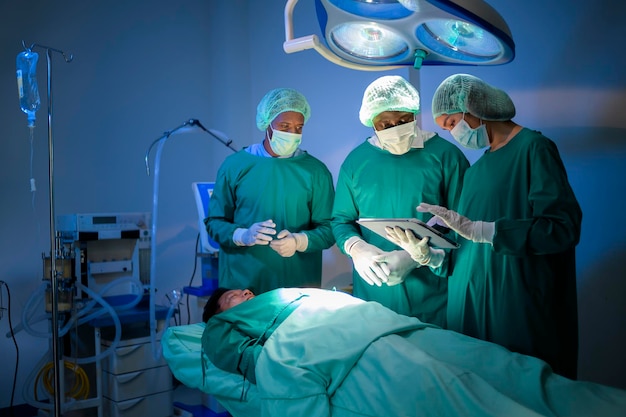 Группа профессиональных хирургов смешанных рас, работающих в операционной концепции здравоохранения больницы