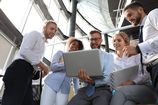 Group of modern business people working together in creative office while standing near the desk.